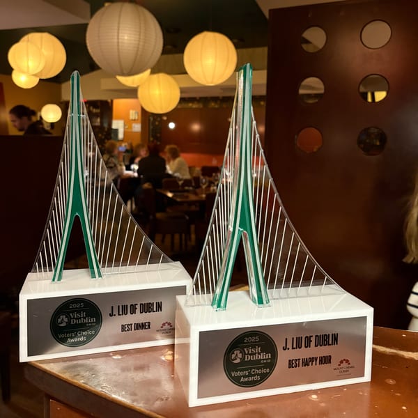 Two J Liu of Dublin awards for "Best Dinner" and "Best Happy Hour" on a bar.