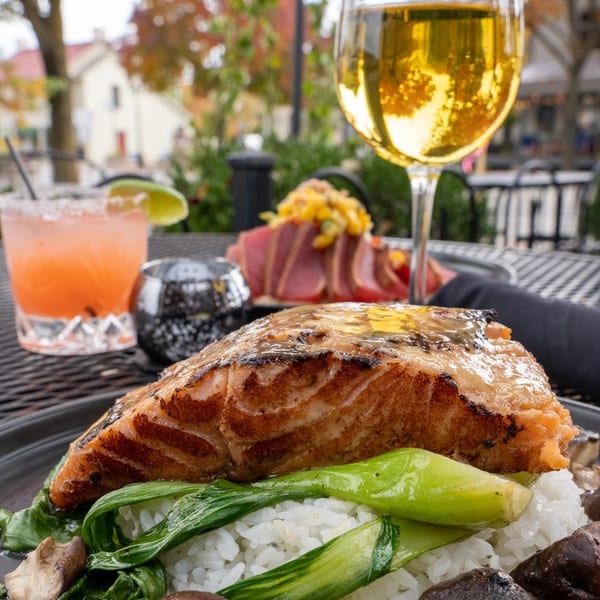 J Liu of Dublin's grilled salmon with bok choy and rice, cocktails, and tuna tataki on a patio.
