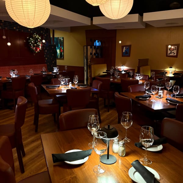 Warmly lit dining room at J Liu of Dublin, featuring wooden tables, leather chairs, and paper lanterns.