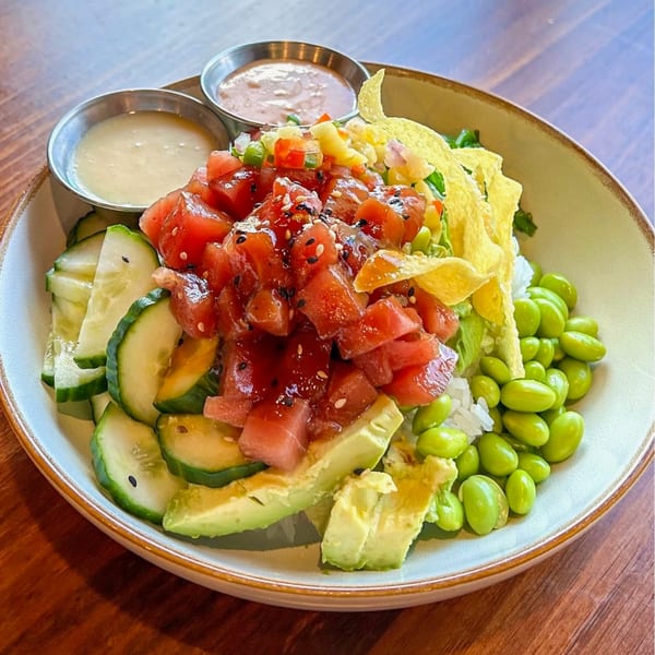 A colorful J Liu of Dublin poke bowl with tuna, avocado, cucumber, edamame, and two sauces.